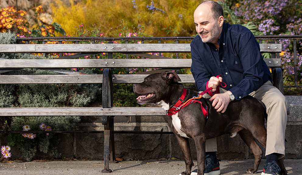 A man and his dog at a park bench.