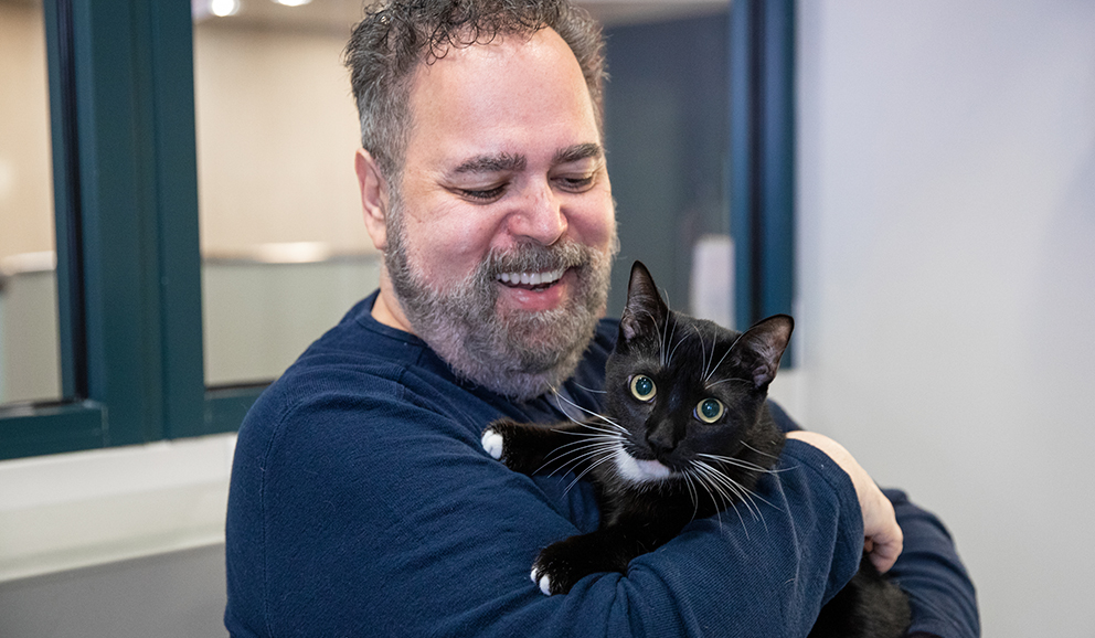 A man smiling at his black cat.